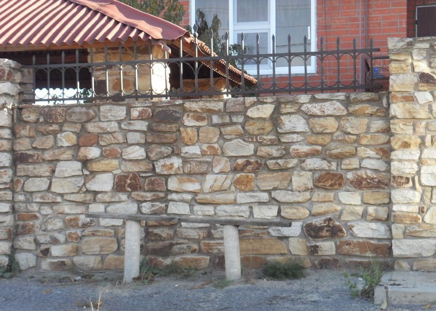 Массивная ограда из бутового камня перед загородным домом