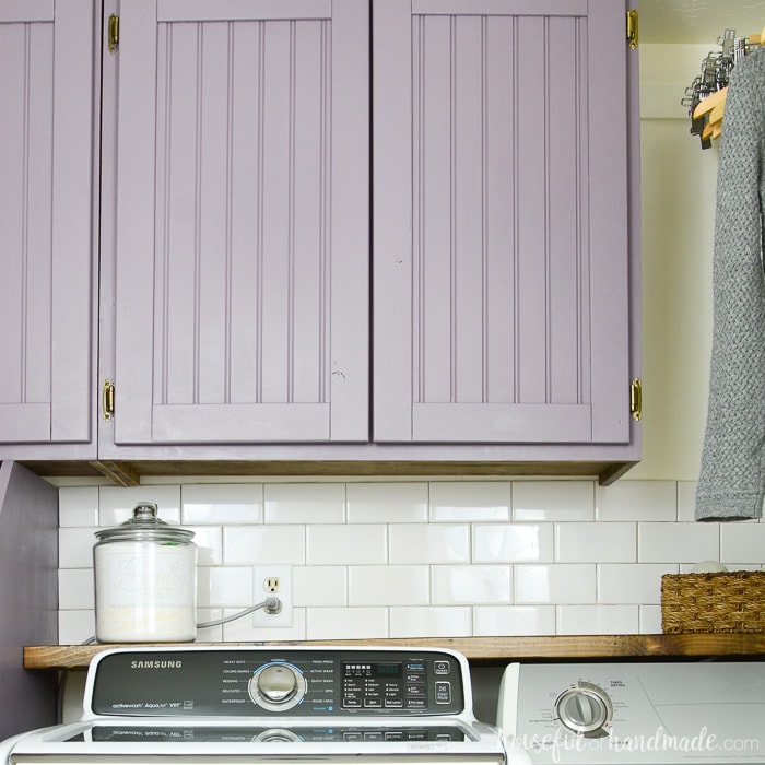 DIY cabinet doors with beadboard center panels painted purple. On cabinets above a washer and dryer. 